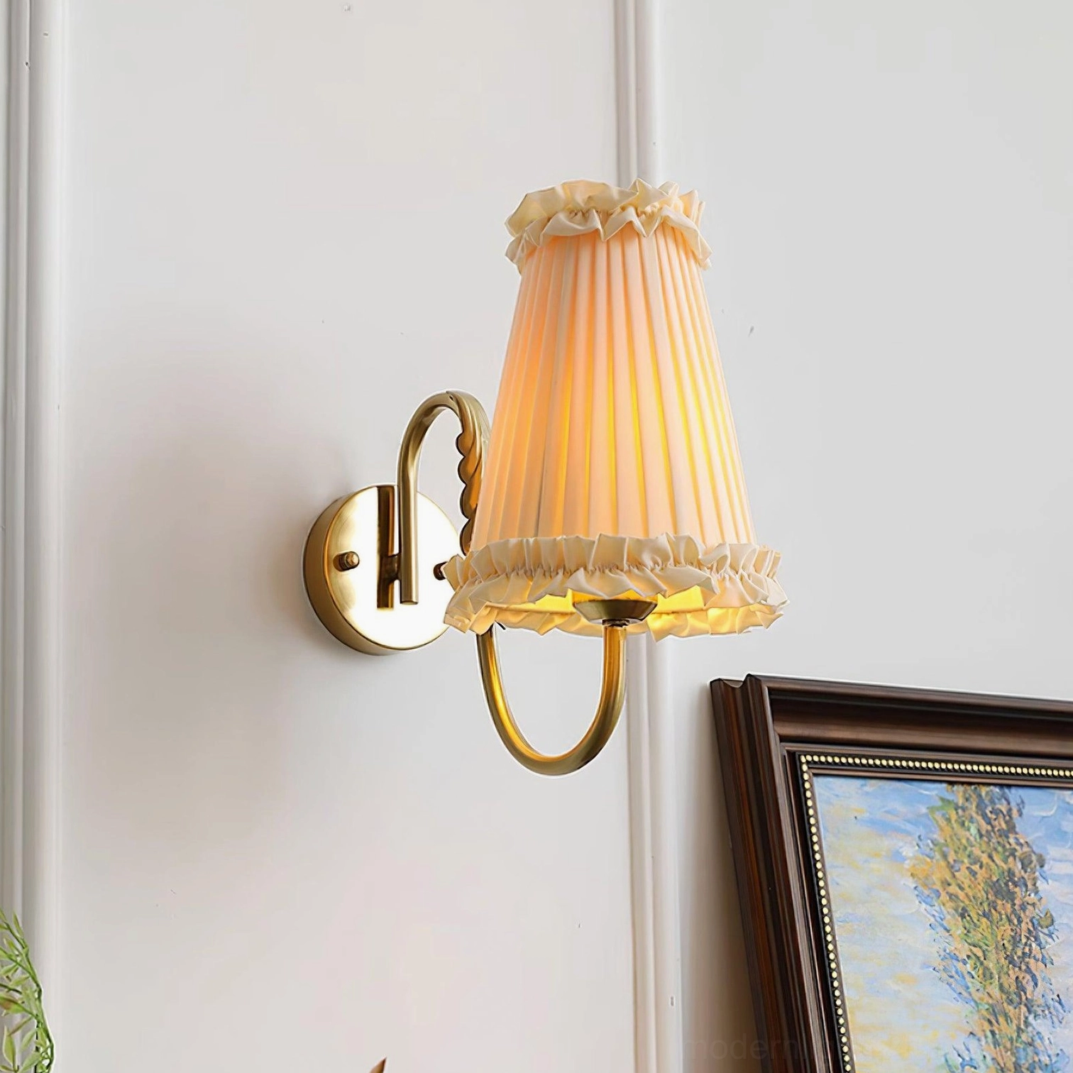 Side profile of gold brass wall sconce showing curved arm and pleated shade detail
