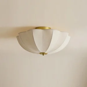 Close-up of Bravelle vintage fabric flush mount with pleated linen shade and brass trim details against neutral beige wall