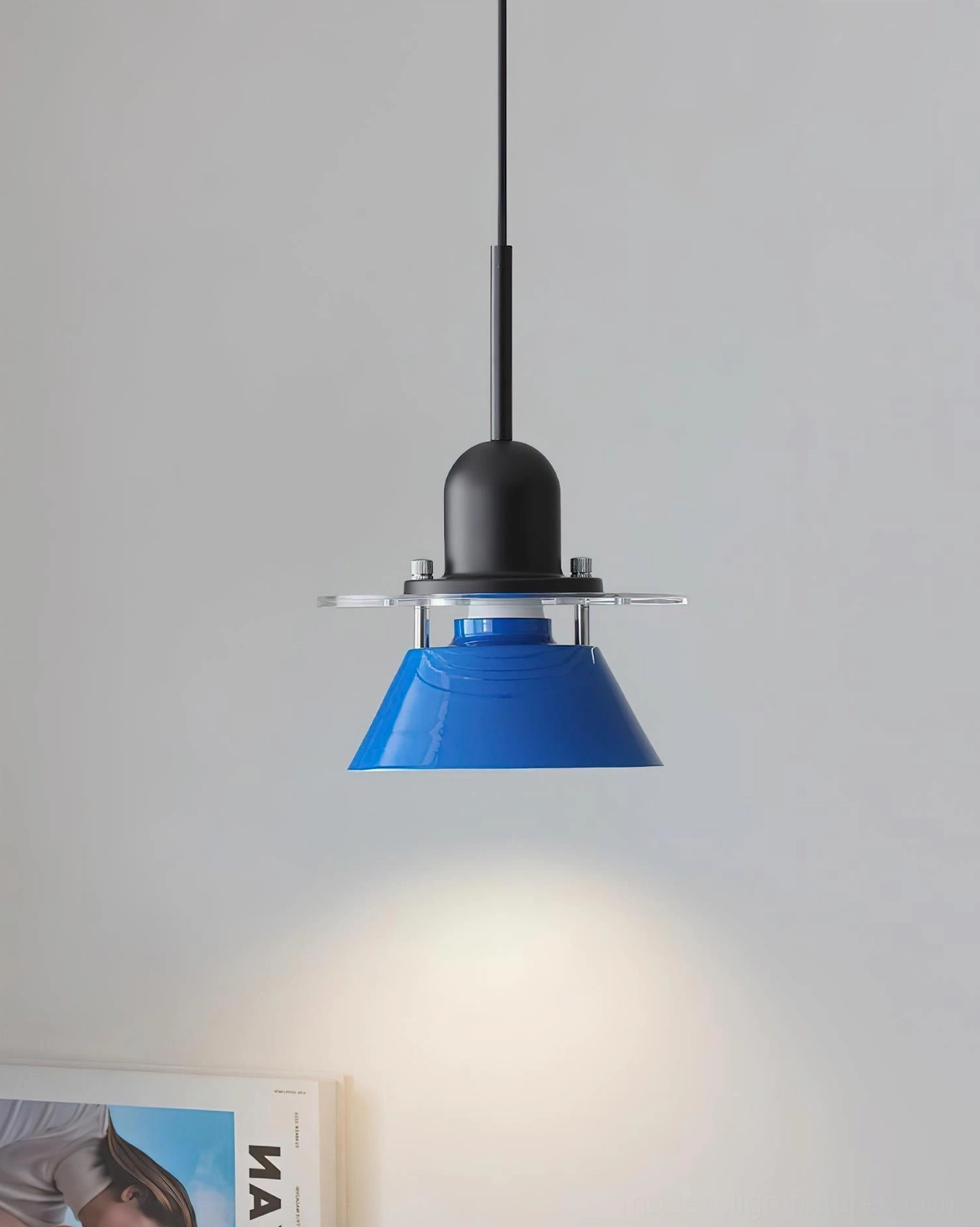 Contemporary blue pendant lamp installed in modern interior with magazine and light gray wall background