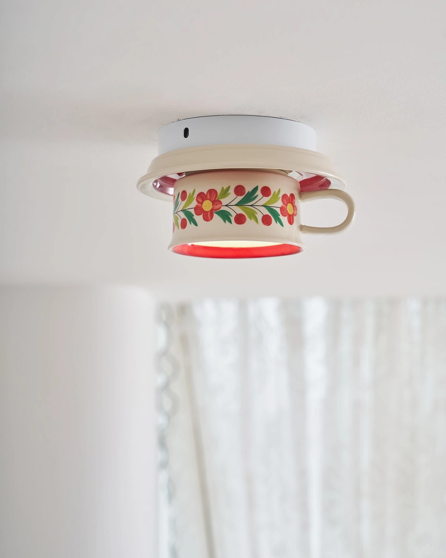 Brisa tea cup ceiling light from below showing warm downward glow and ceramic sculptural form installation detail