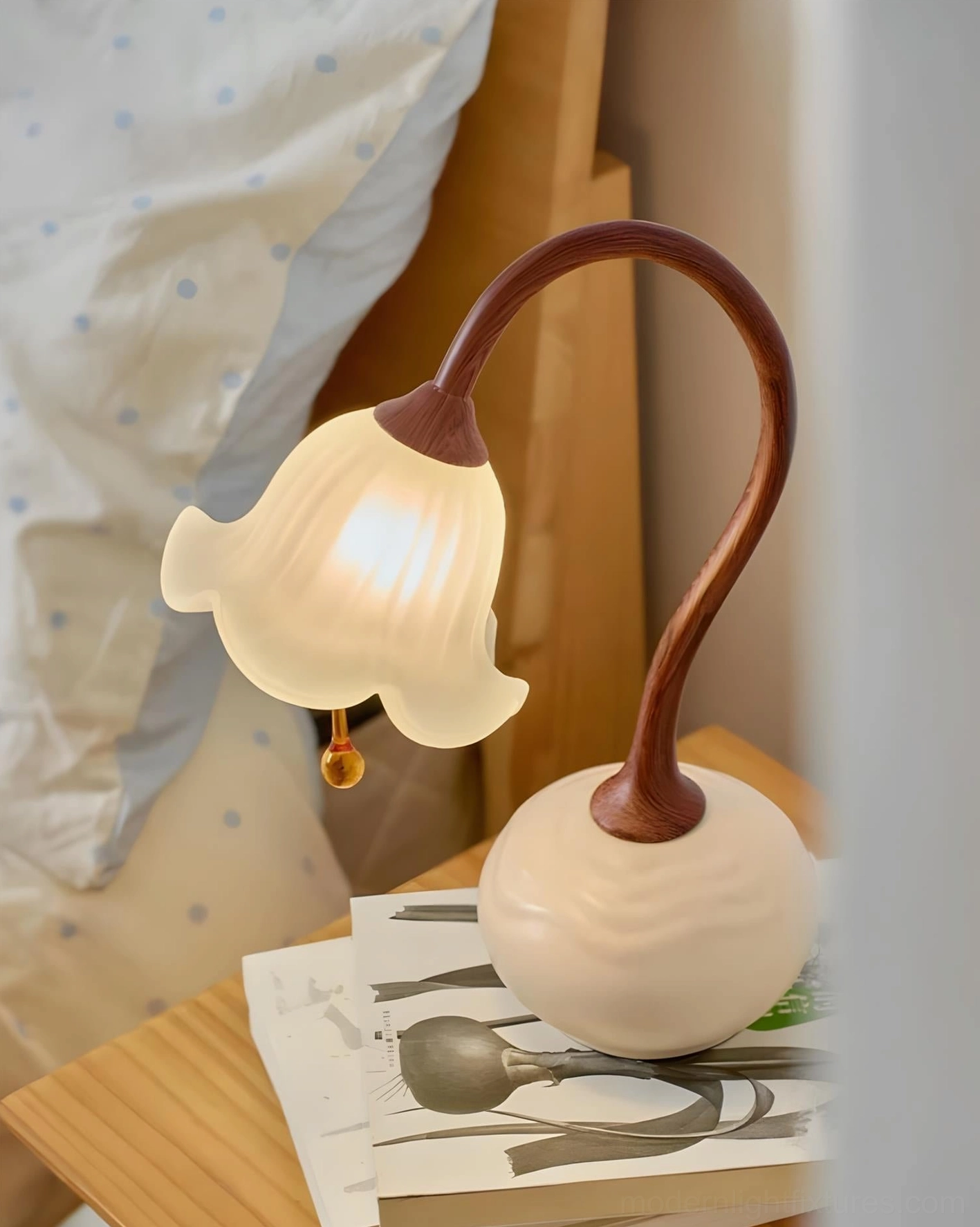 Brivana table lamp illuminated on bedroom nightstand with stacked magazines - warm frosted glass glow