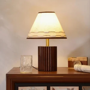 Handcrafted wooden table lamp with walnut finish base displayed on vintage wooden side table with glass cup and camera decor
