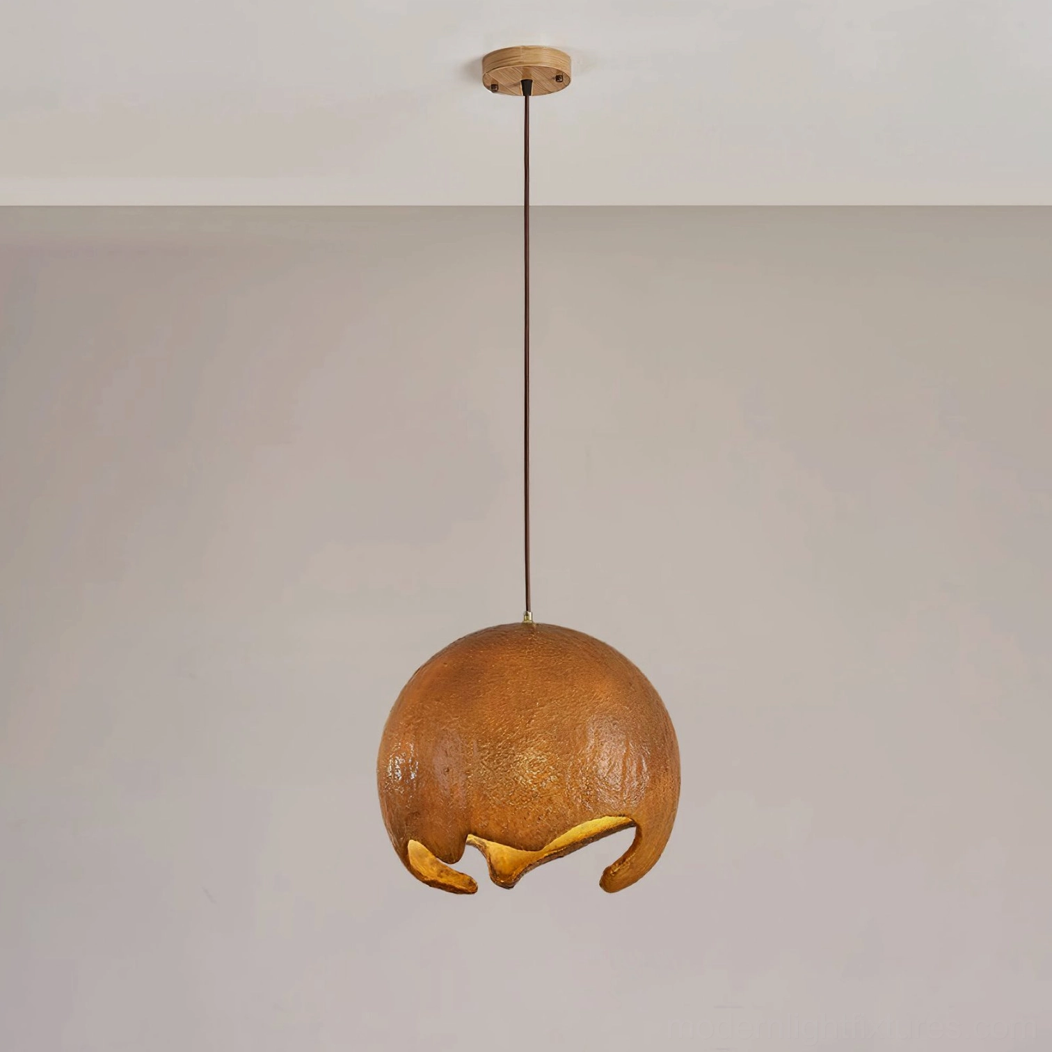 Brown moon crater pendant lamp hanging from wooden ceiling mount with black cord, displaying rough texture and warm light diffusion