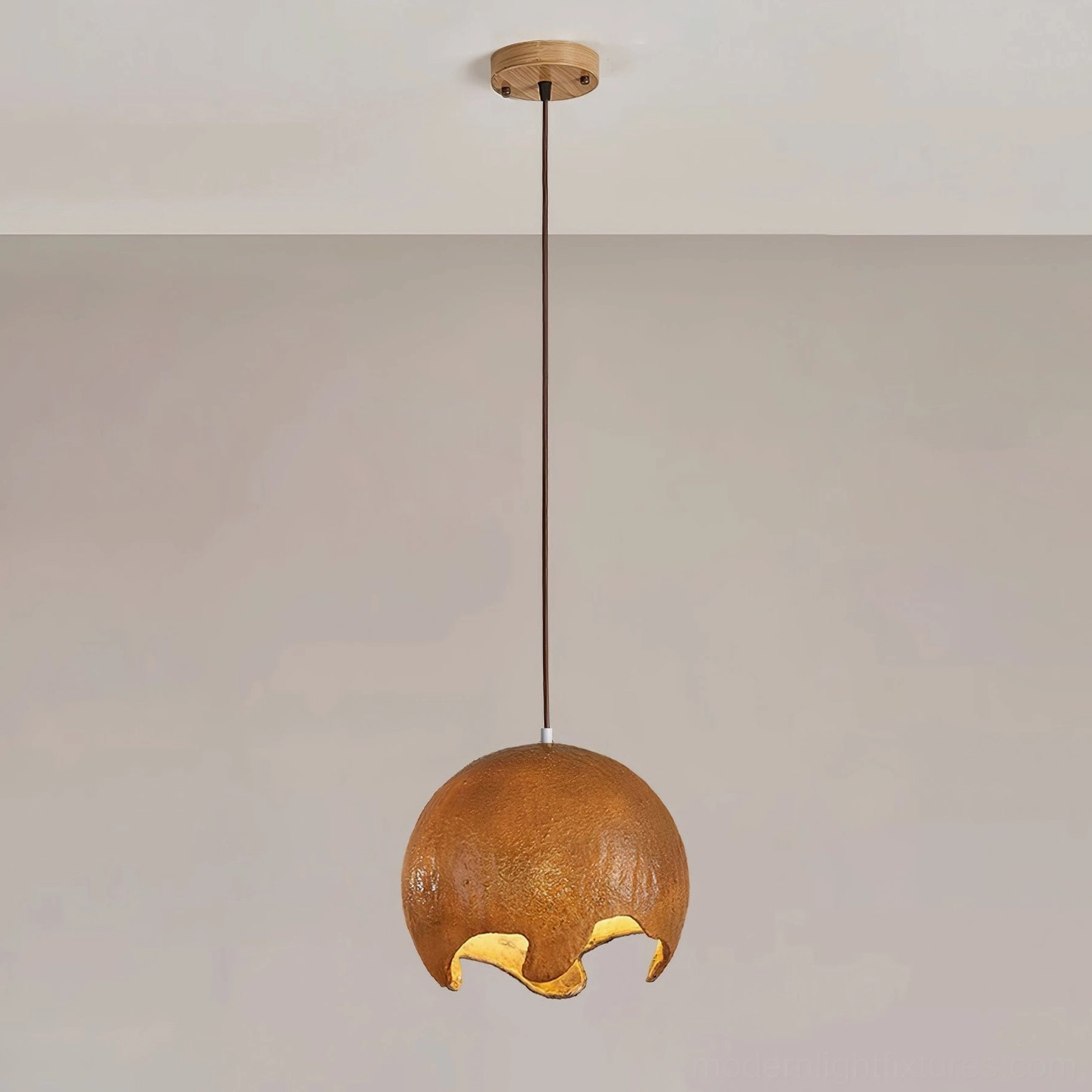 Brown moon crater pendant light with medium textured resin shade suspended from wooden ceiling, organic crater surface illuminated