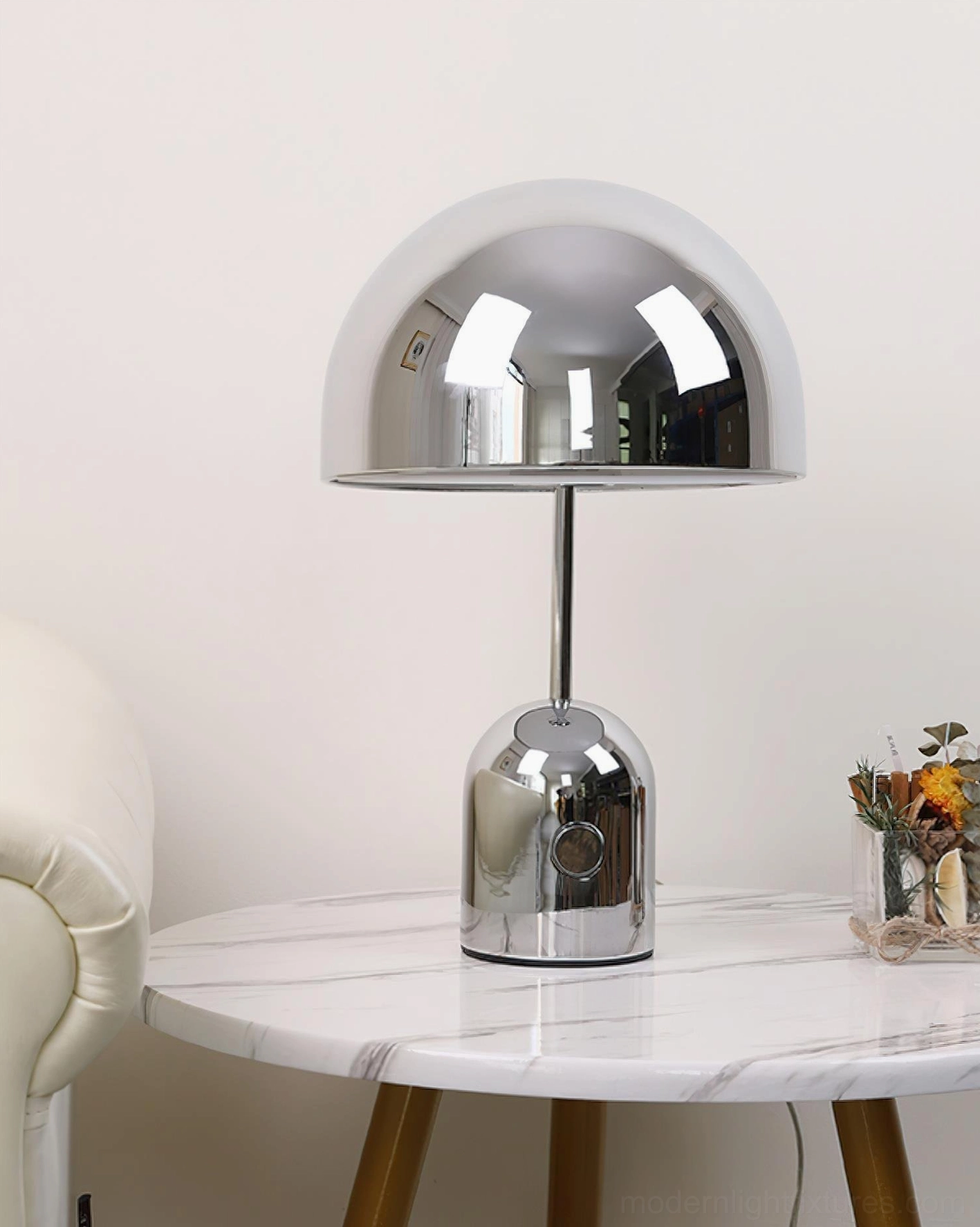 Chrome silver Brulee portable lamp on marble side table in living room with floral decorative accents