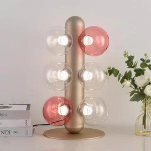 Modern glass bubble table lamp on tabletop with books and flowers, warm glowing ambient lighting, luxury home décor