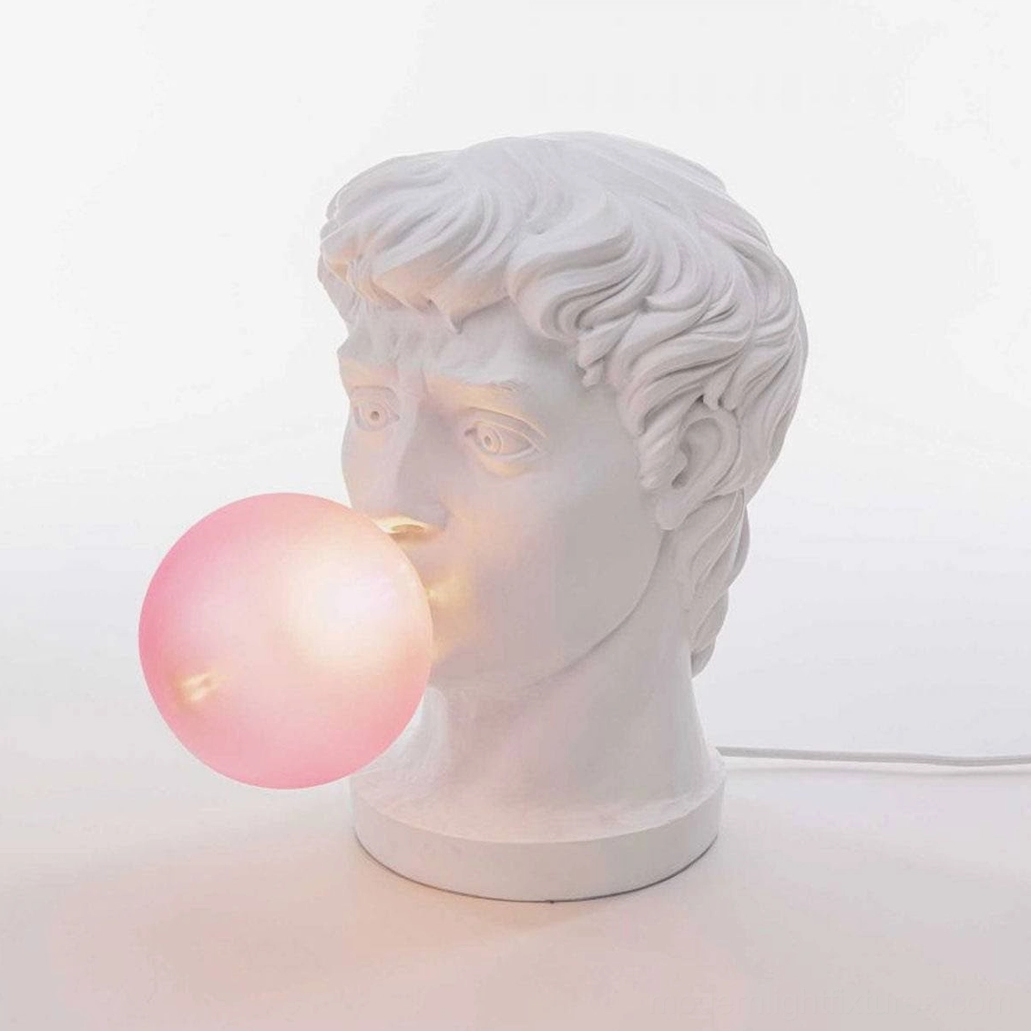 Bubblegum Boy sculptural table lamp three-quarter view with illuminated pink frosted glass globe on white background