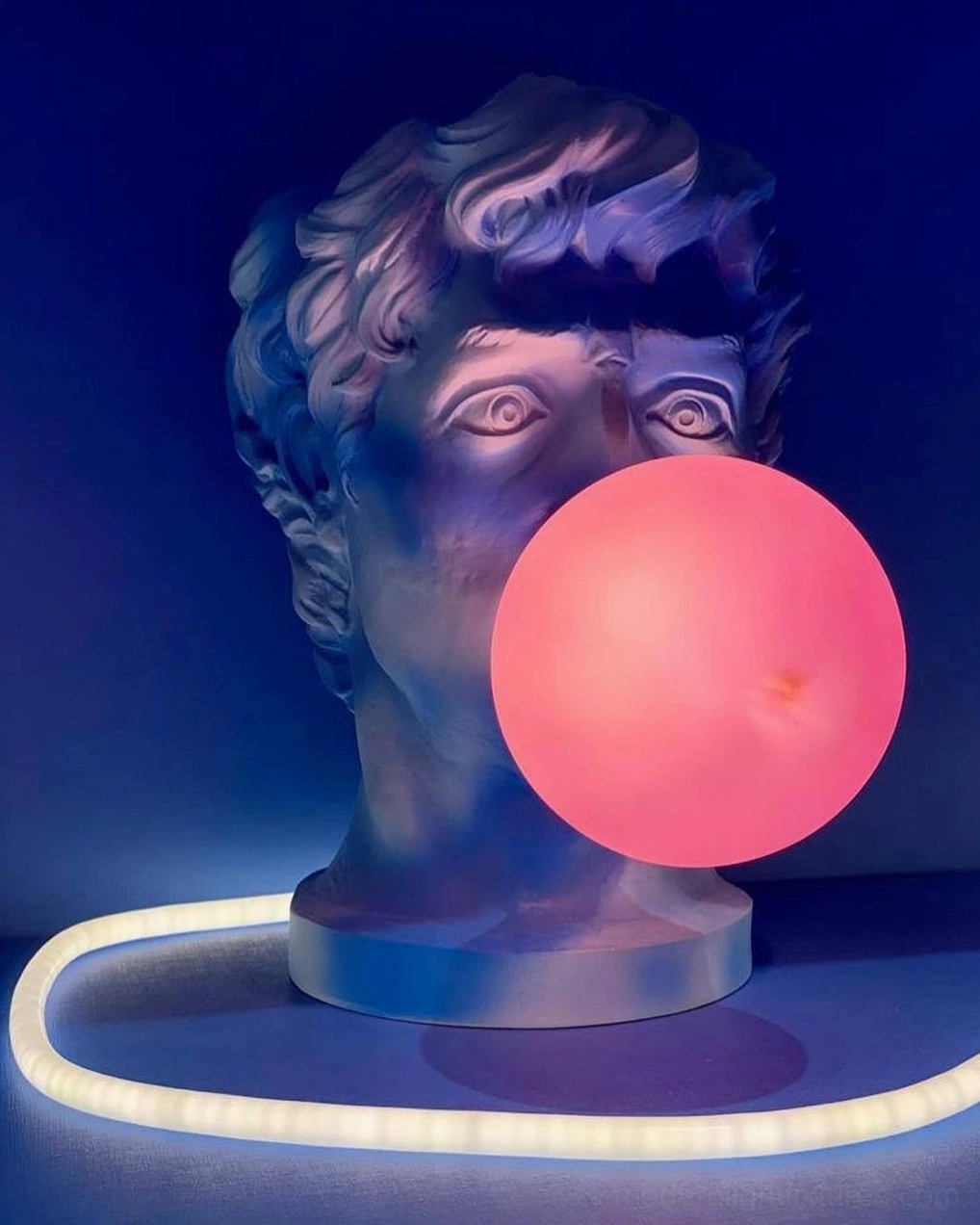 Bubblegum Boy table lamp with ambient ring lighting against dark blue studio background creating moody atmosphere