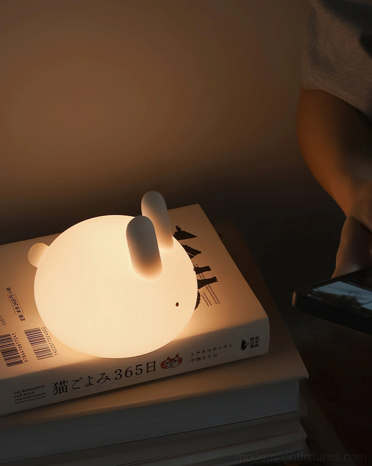 Glowing bunny lamp placed on Japanese books at reading desk, compact size demonstration
