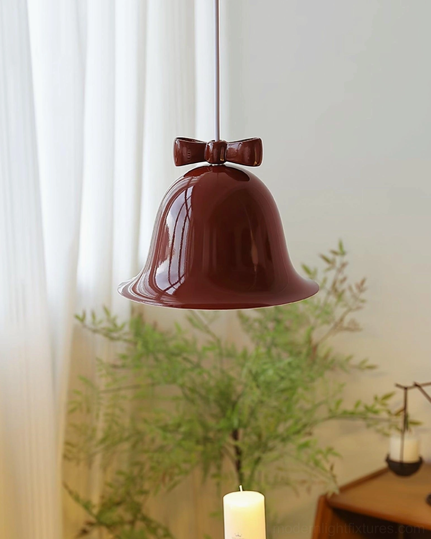 Deep burgundy ceramic bell pendant lamp in rustic home corner with potted plants and candles