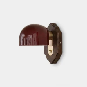 Burgundy glass dome wall sconce with walnut wood backplate and brass arm, front studio view on white background