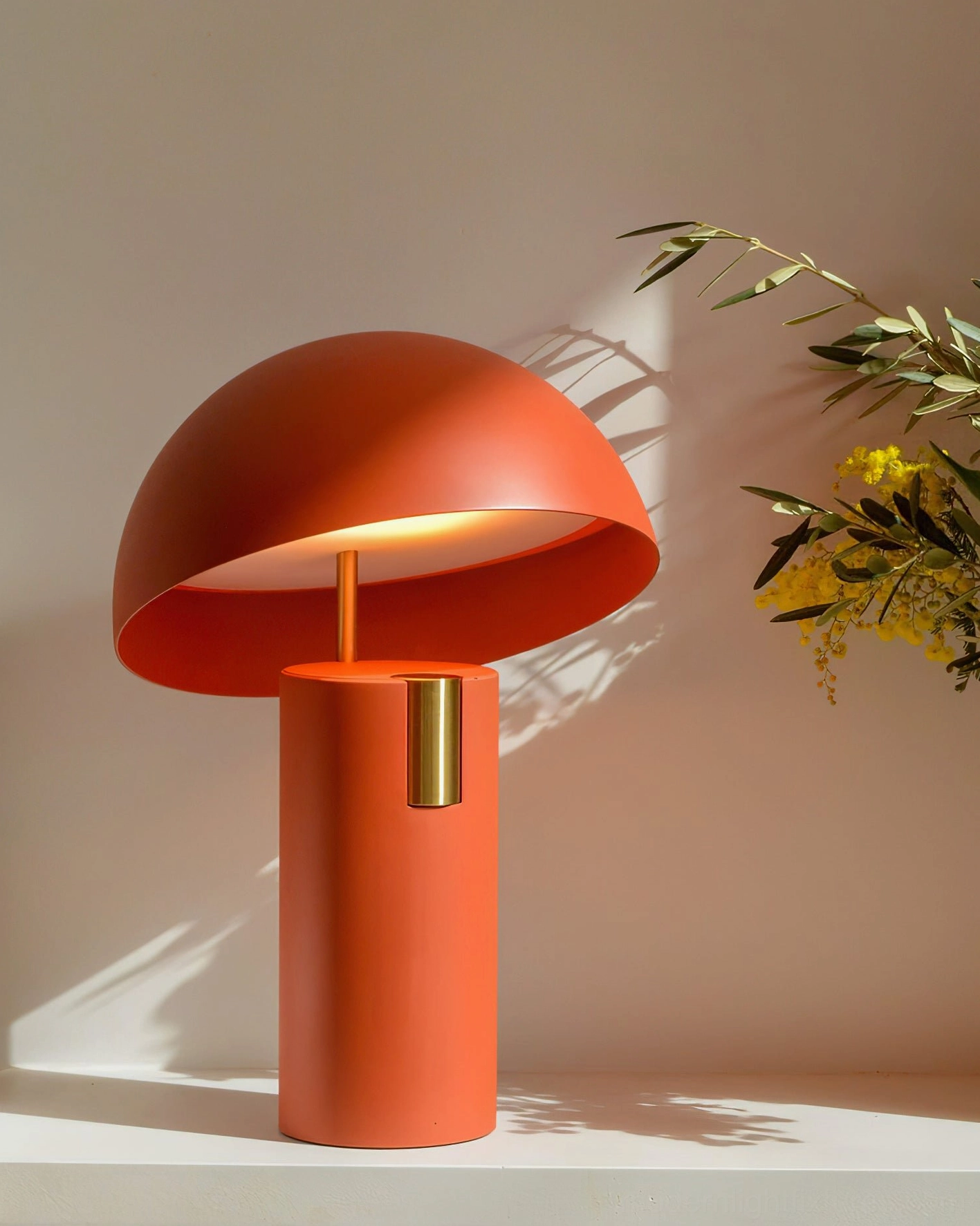 Burnt orange Avo mushroom table lamp with brass accent, three-quarter view on styled tabletop with foliage