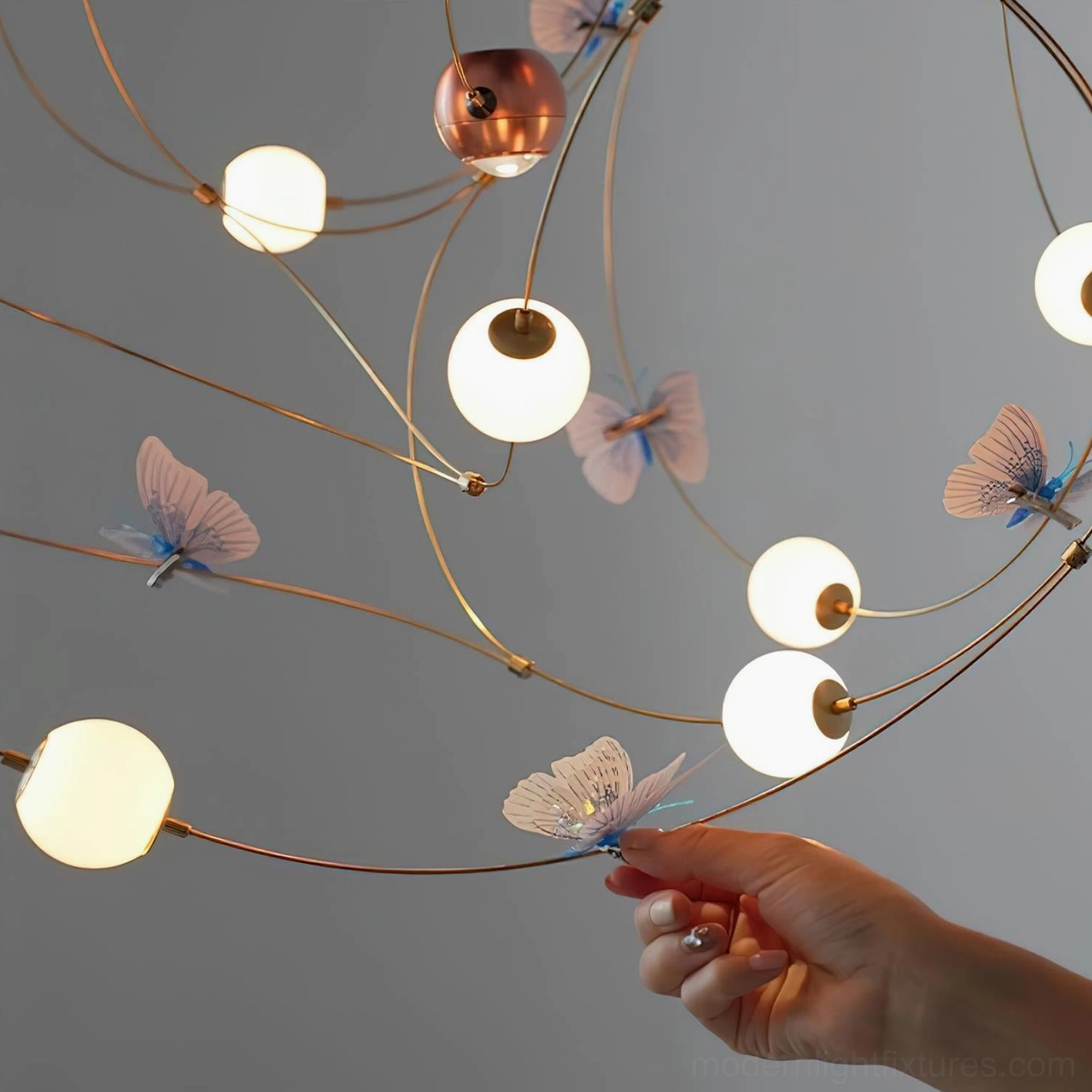 Butterfly pendant chandelier with delicate brass wire framework and translucent sphere elements in warm ambient lighting