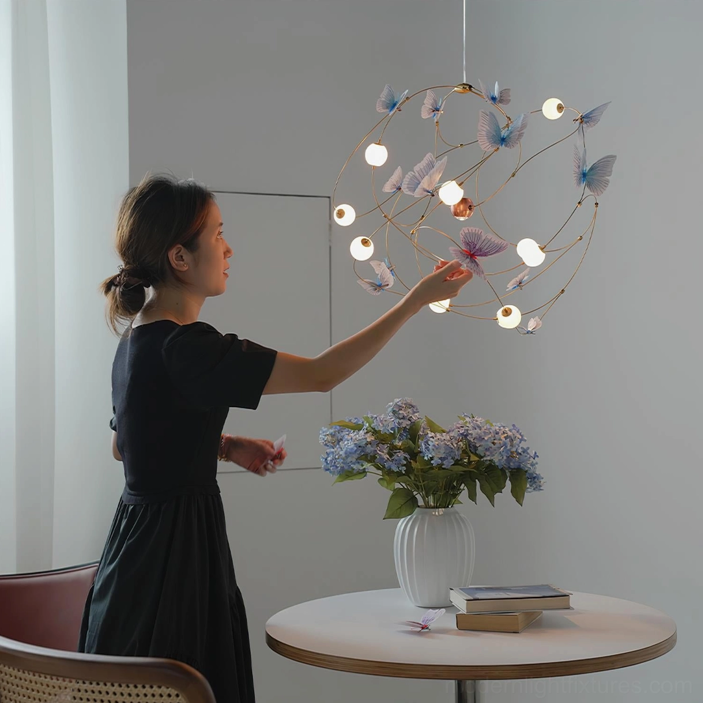 Butterfly pendant chandelier installed above dining table with mixed color butterfly ornaments creating layered warm ambient lighting in home setting