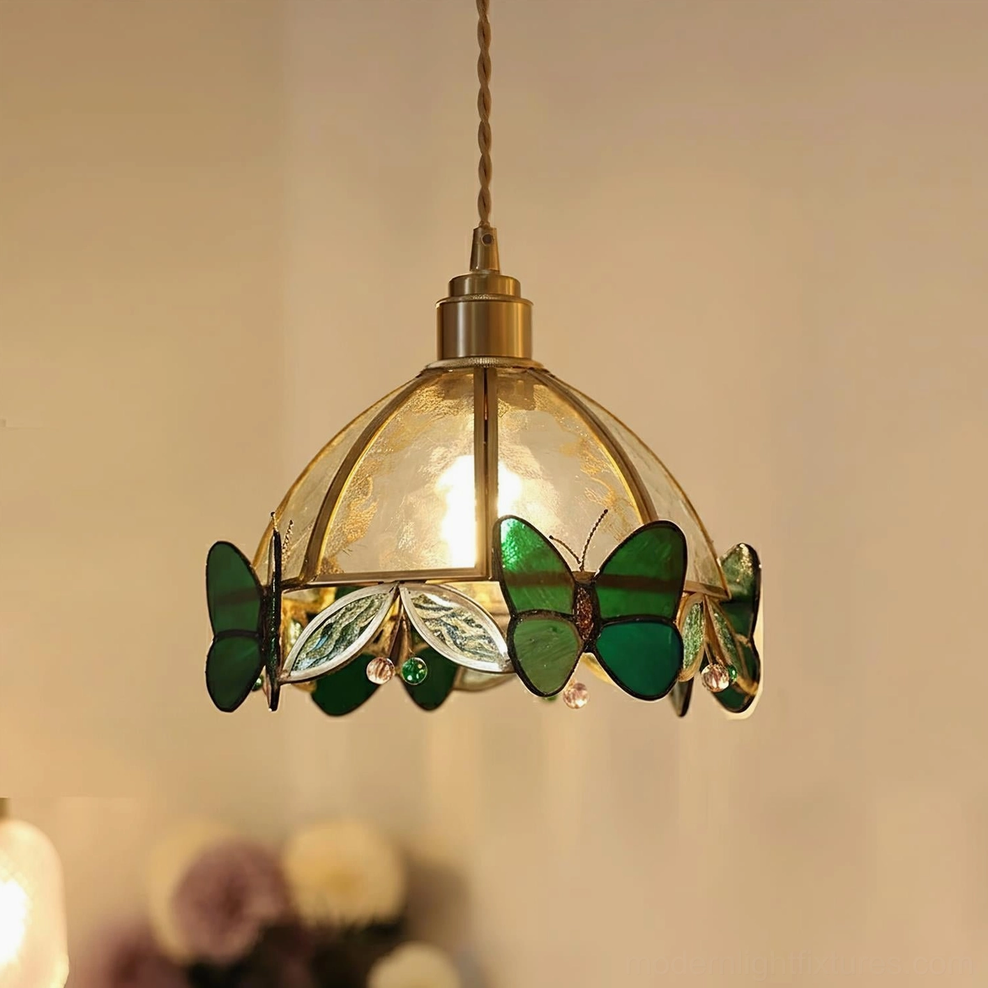 Green butterfly stained glass pendant light with brass finish and textured glass shade in natural light