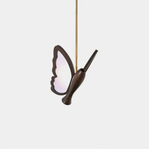 Butterfly pendant light with frosted acrylic wings and dark brown sculptural body, shown in studio setting with brass hanging rod