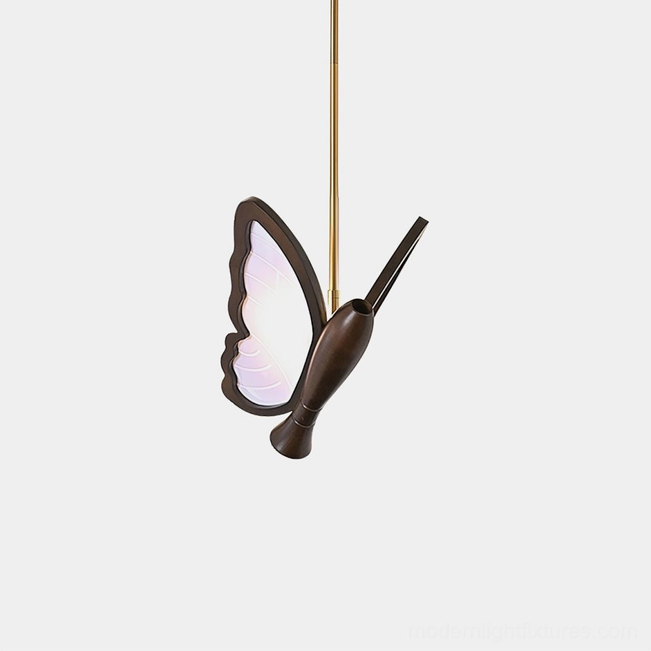 Butterfly pendant light with frosted acrylic wings and dark brown sculptural body, shown in studio setting with brass hanging rod