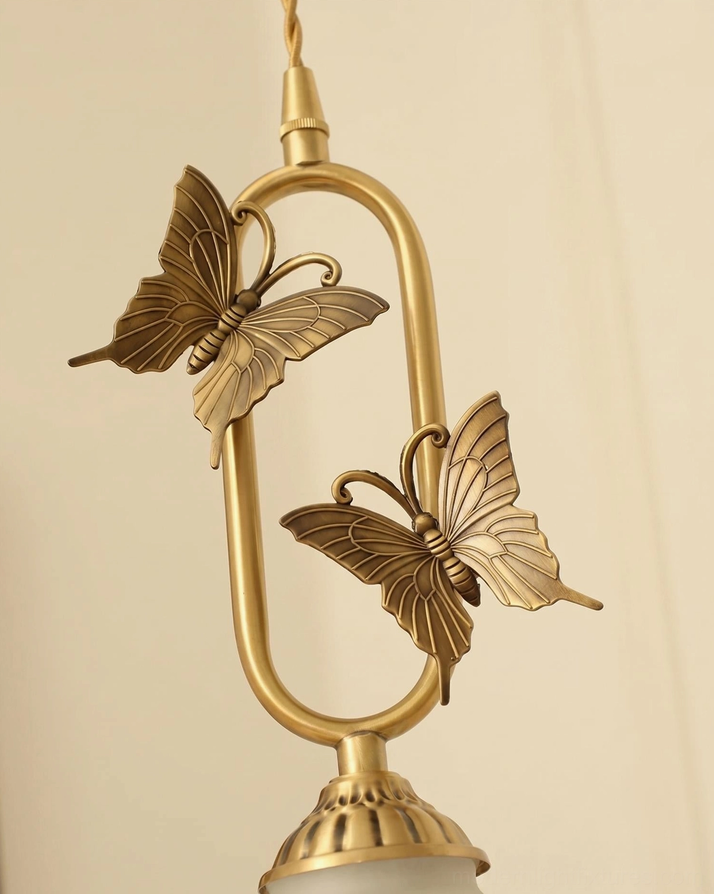 Brass butterfly pendant light with twisted fabric cord showing 59-inch adjustable height mechanism at canopy