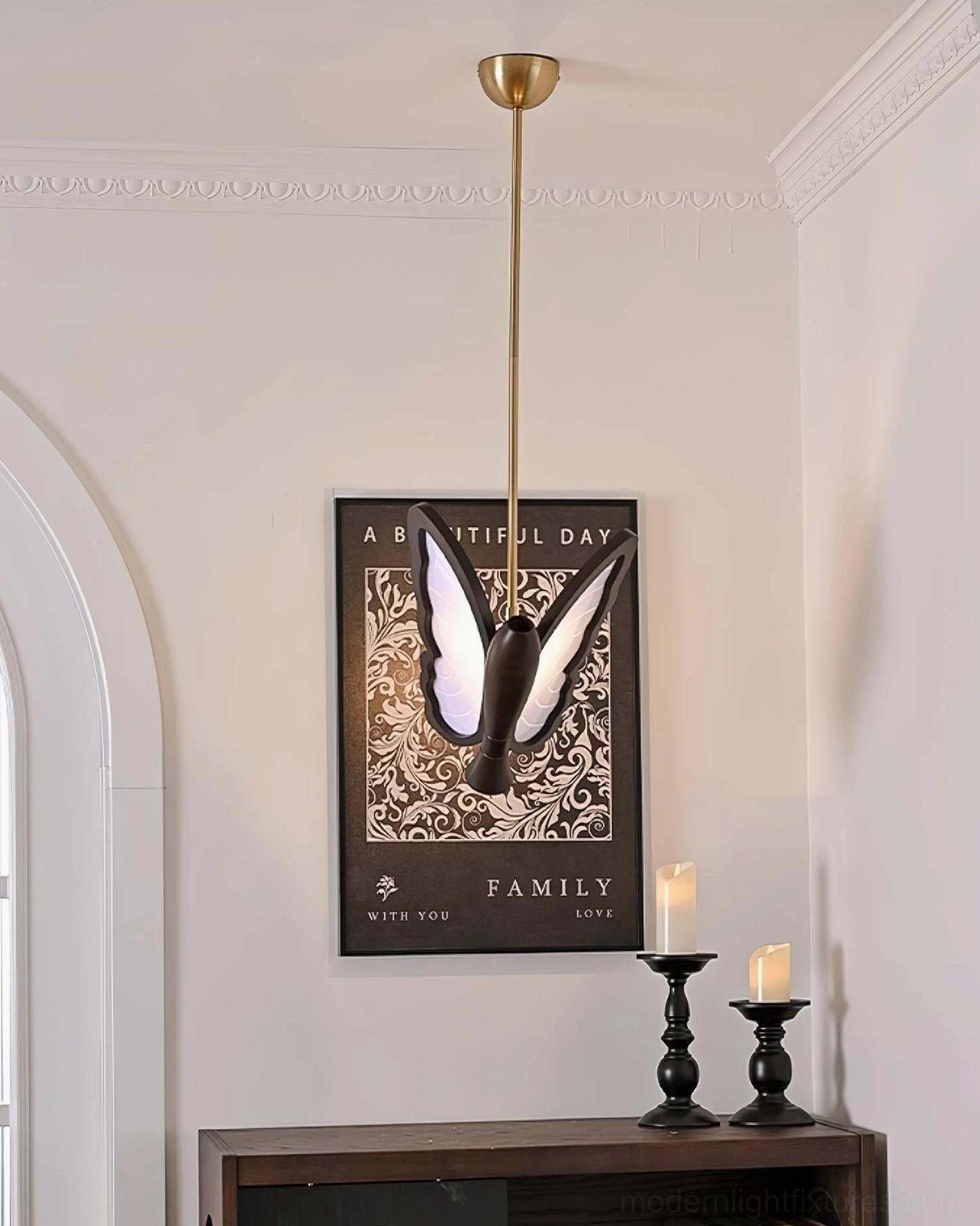 Butterfly pendant lamp installed under ceiling cornice in modern living room above console table with neutral wall tones