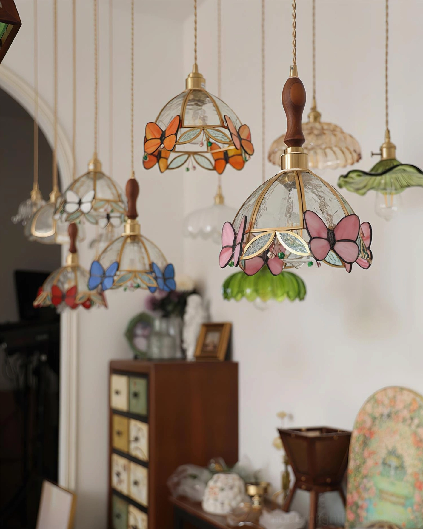 Showroom display of decorative butterfly pendant lights in various colors with different brass hardware styles