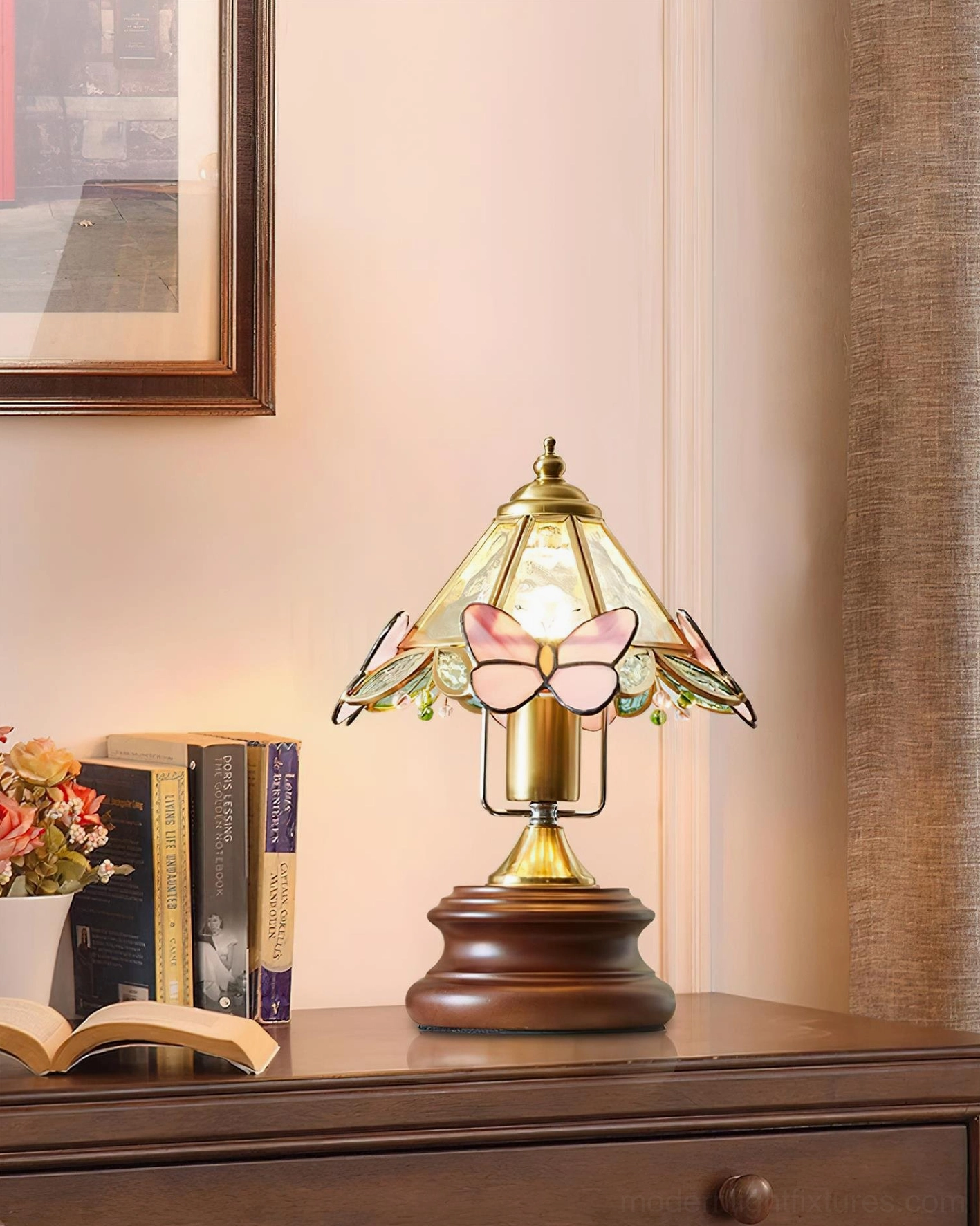 Pink butterfly lamp creating warm ambient lighting on bedroom bedside table with books and floral decor