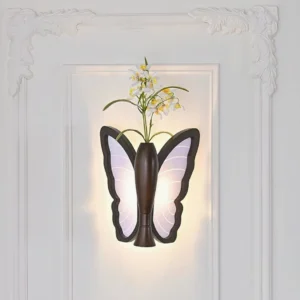 Butterfly wall lamp with integrated flower vase featuring fresh botanical arrangement, glowing acrylic wings, installed on carved decorative white wall panel