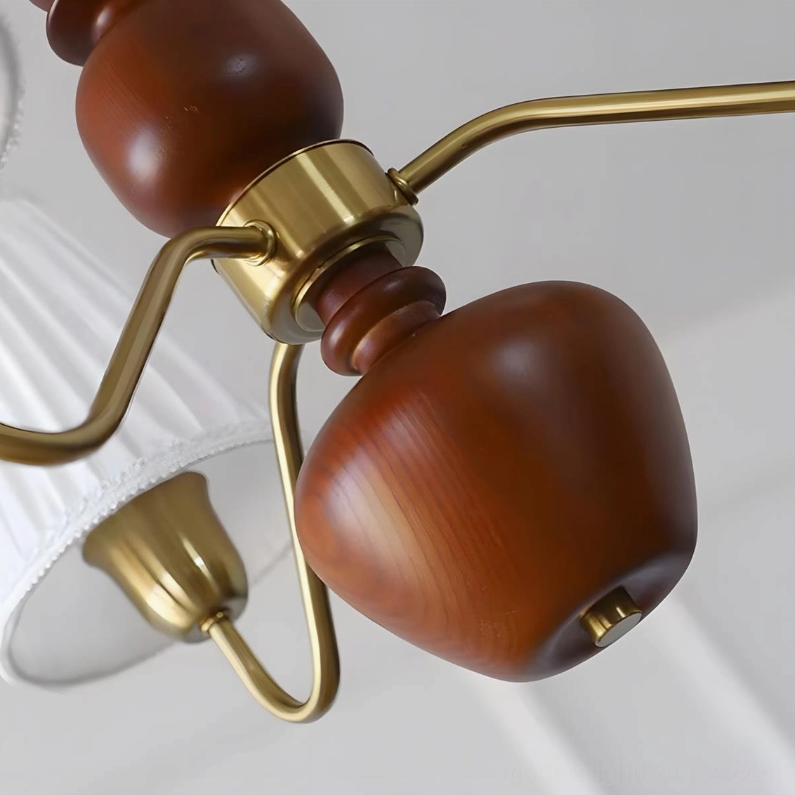 Cadenza chandelier detail view - pleated fabric shades, brass framework, and sculptural wood elements