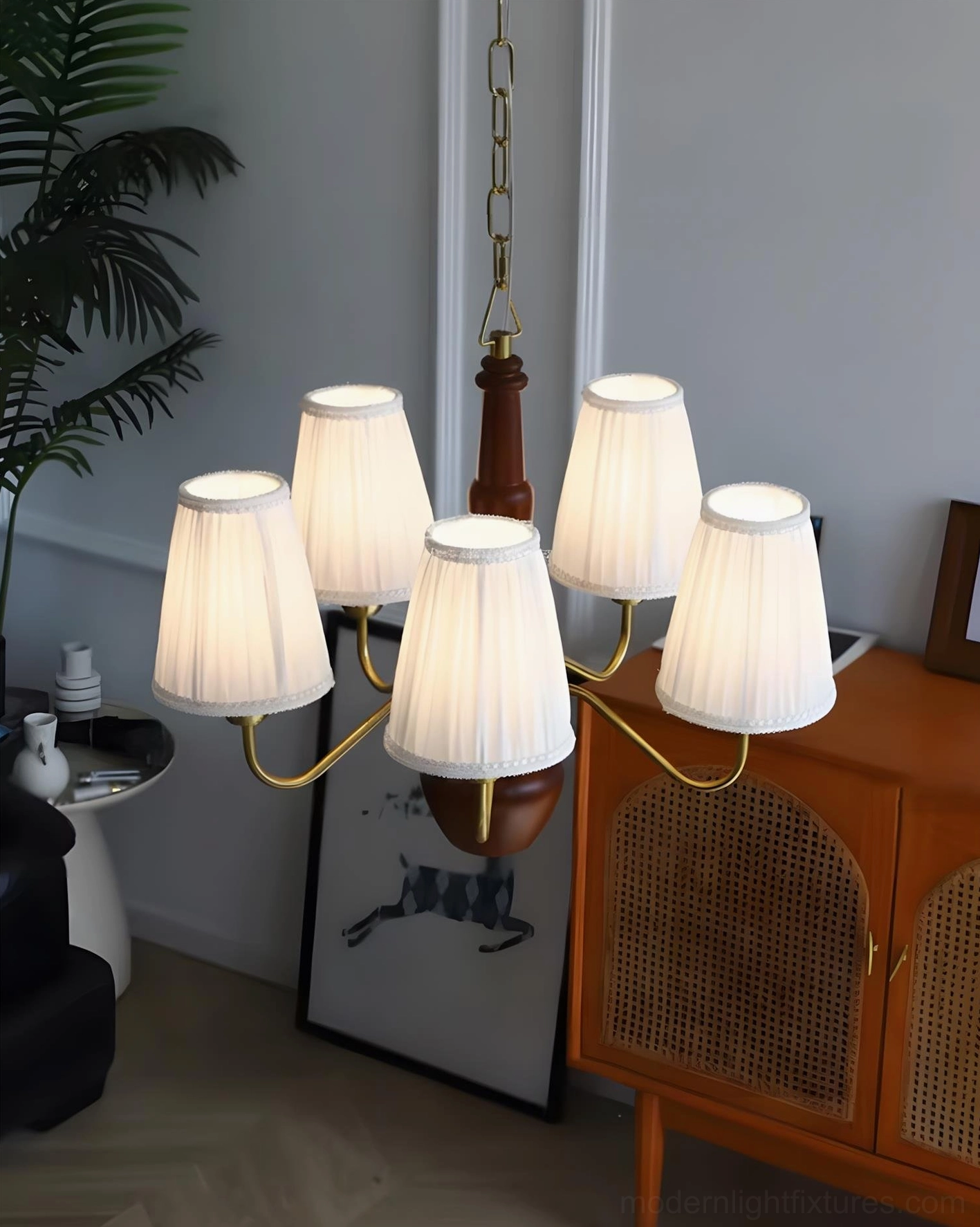Side view of fabric chandelier showing brass lamp arms, brown wood accents, and pleated white shades