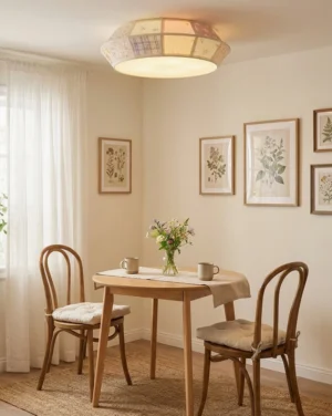 Patchwork fabric ceiling light fixture in dining area with wooden table and botanical wall art - warm farmhouse style lighting