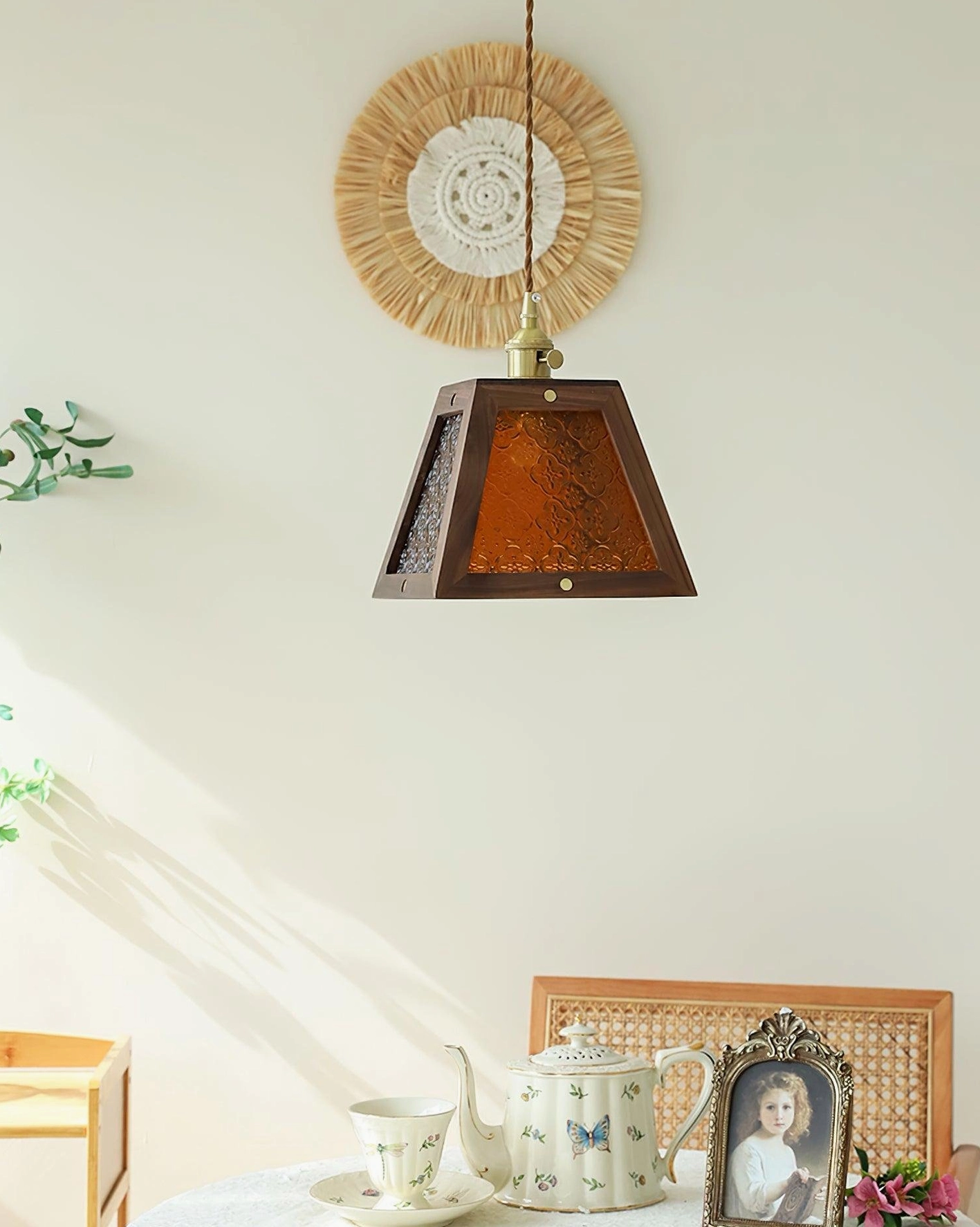 Amber embossed glass pendant lamp with dark wood frame, side angled view in illuminated dining corner