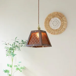 Trapezoidal glass pendant light with amber patterned shade and brass hardware, displayed in cozy home setting