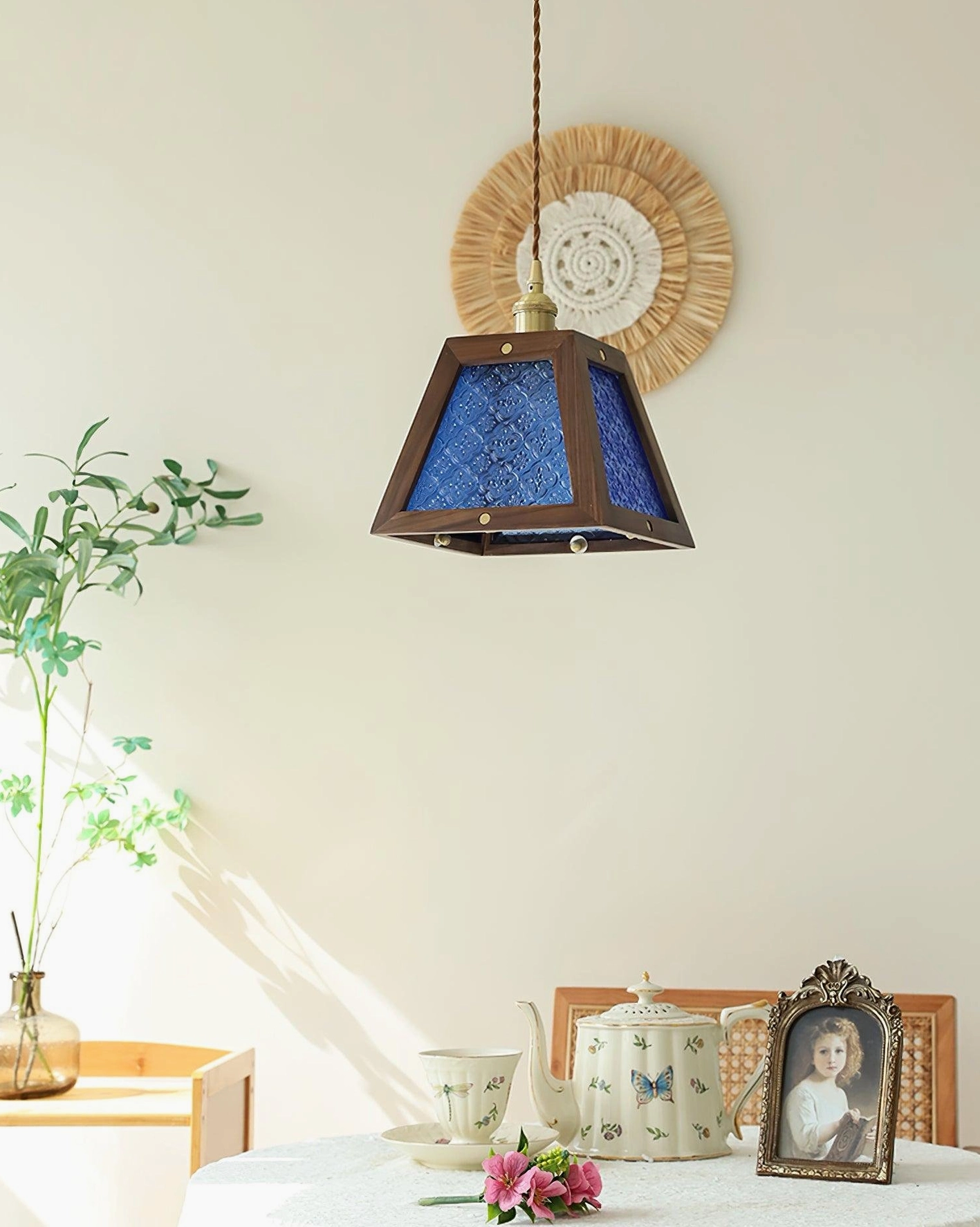 Calvi pendant lamp with blue embossed glass shade hanging over dining table with tableware and decor