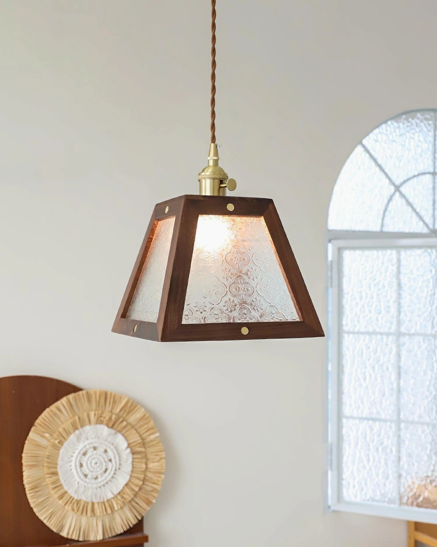 Vintage glass pendant light with frosted shade and dark wood frame, angled view with arched window backdrop