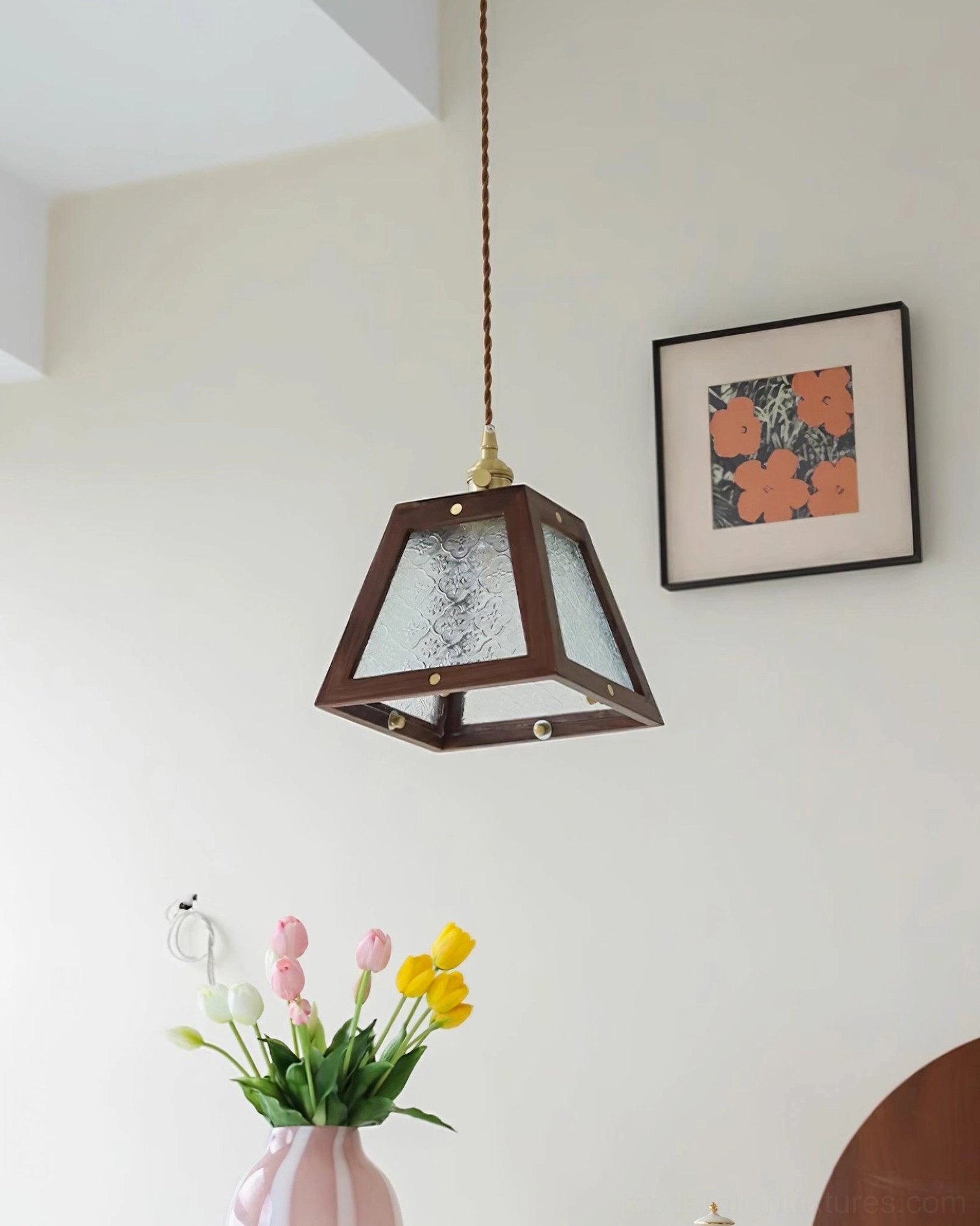 Pendant light fixture with patterned glass shade casting warm colorful glow in home setting