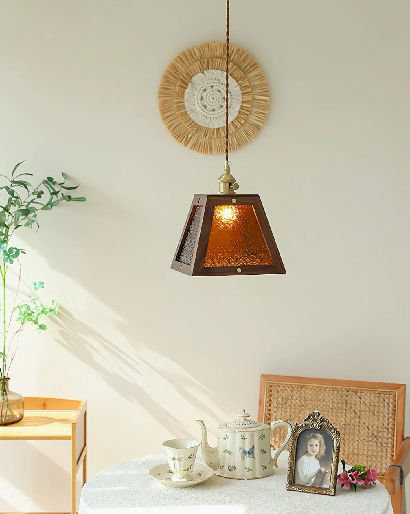 Trapezoidal pendant lamp with illuminated amber glass shade in cozy home corner with plants and decor