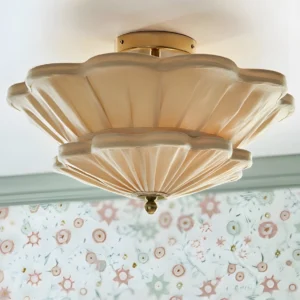 Calyra pleated fabric ceiling fixture overhead close-up with floral wallpaper backdrop, showing scalloped petal edges and polished brass gold canopy
