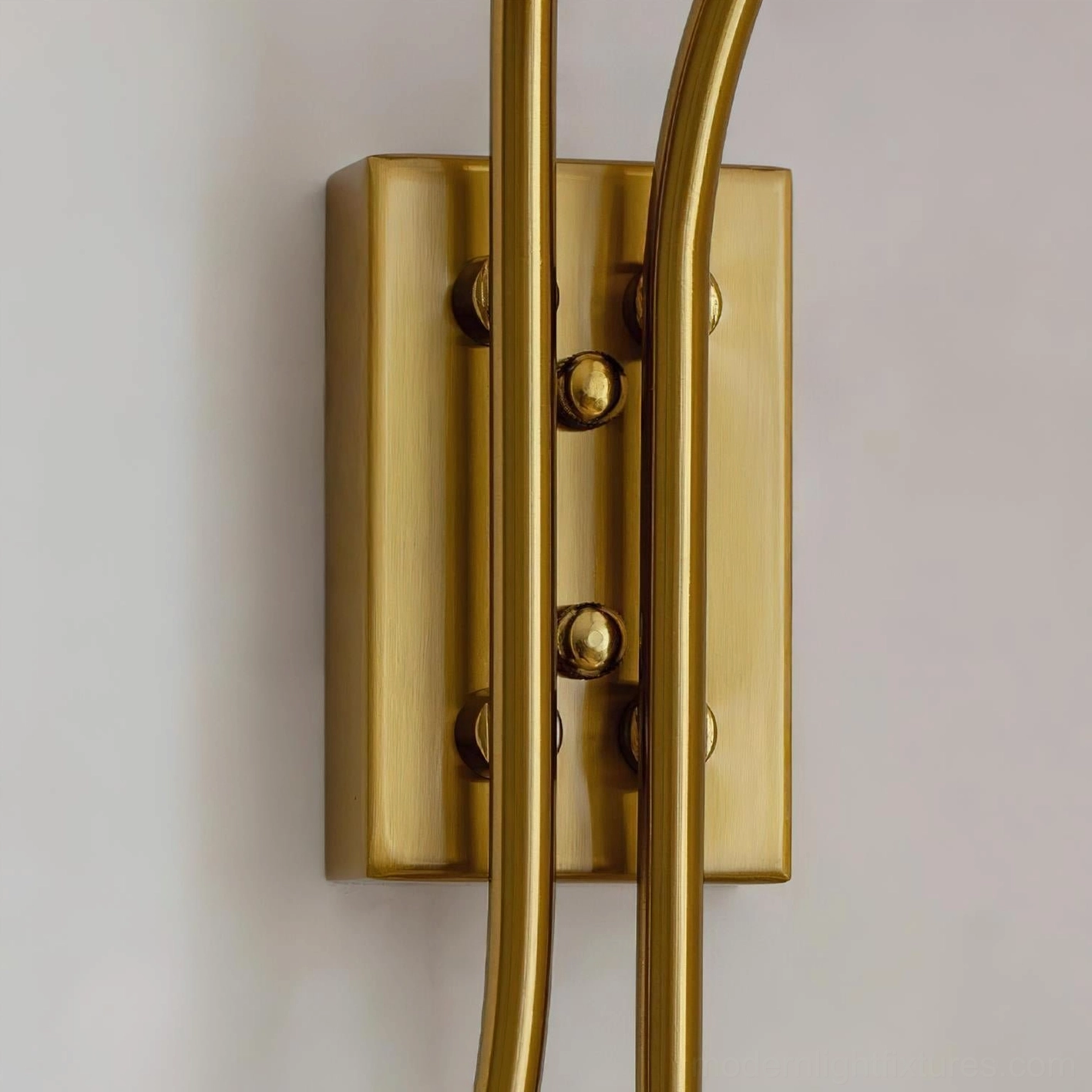 Polished brass gold mounting base and curved stems of Calyssa wall sconce with installation hardware detail