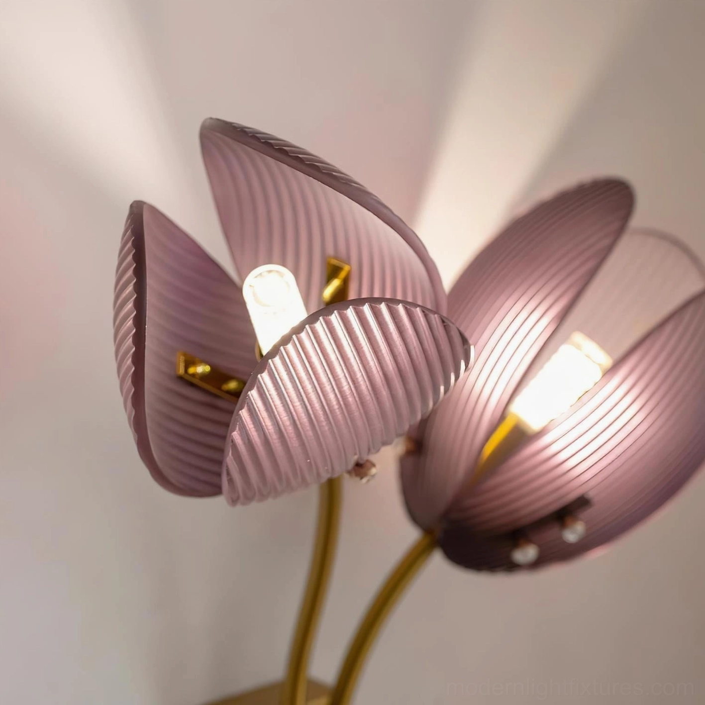 Macro close-up of Calyssa wall sconce dusty pink ribbed glass shade with visible internal bulb and pearl-like decorative accents