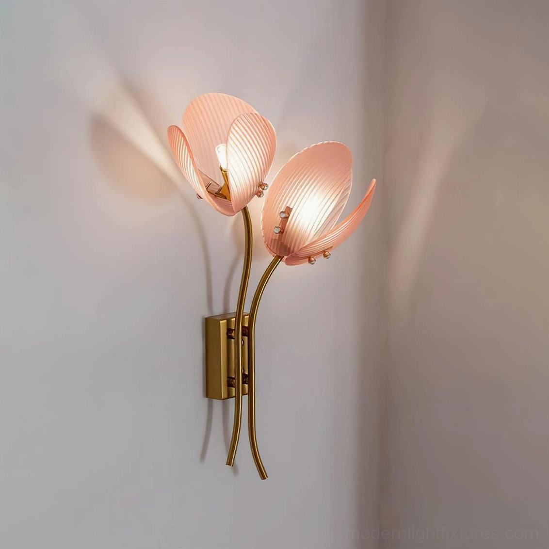 Close-up of Calyssa wall lamp with warm peach-pink ribbed glass petals illuminated in bedroom setting