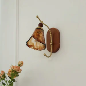 Calyx wall lamp with amber conical glass shade and brass metal arm mounted on indoor wall