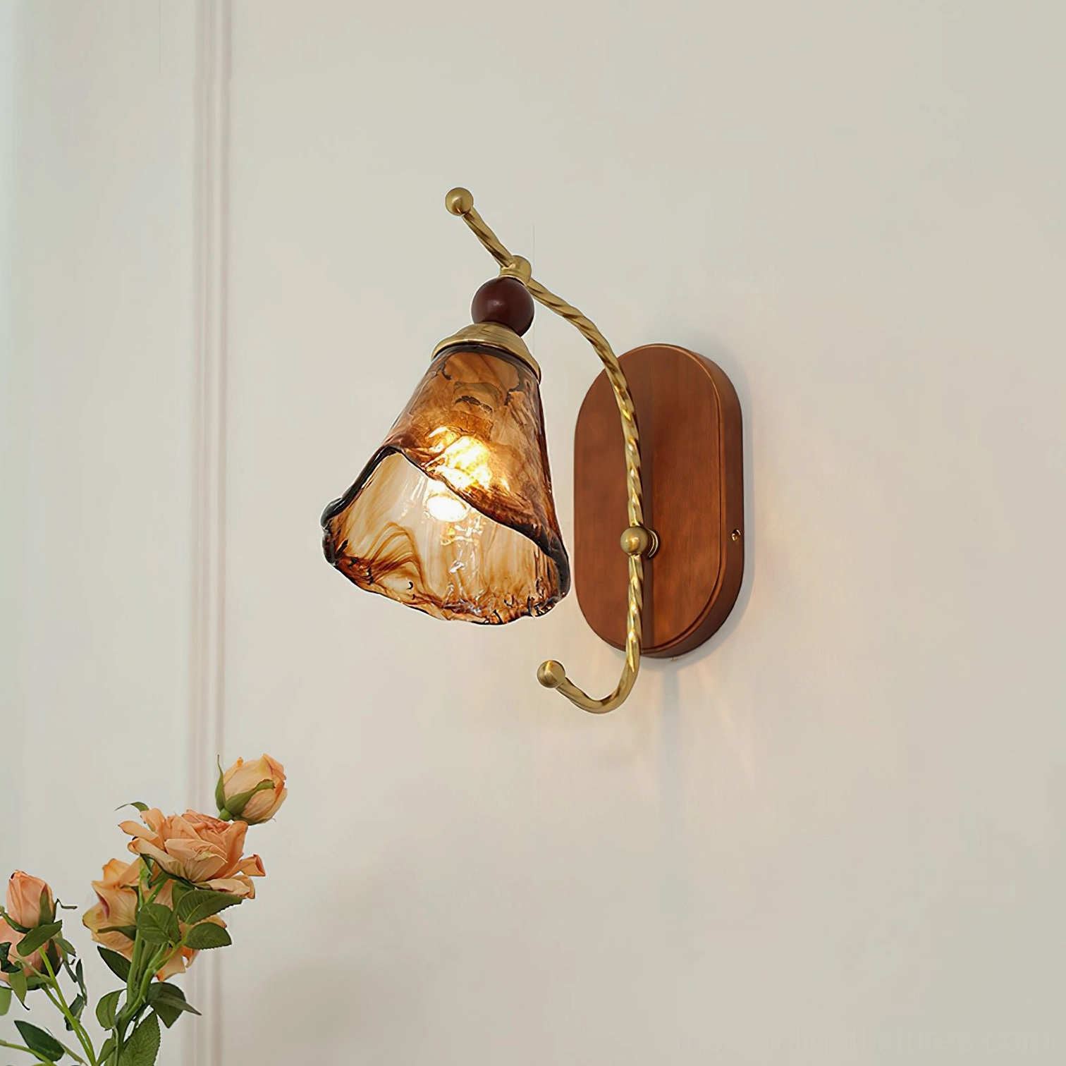 Calyx vintage wall sconce with illuminated amber glass shade and twisted brass hardware on gray wall