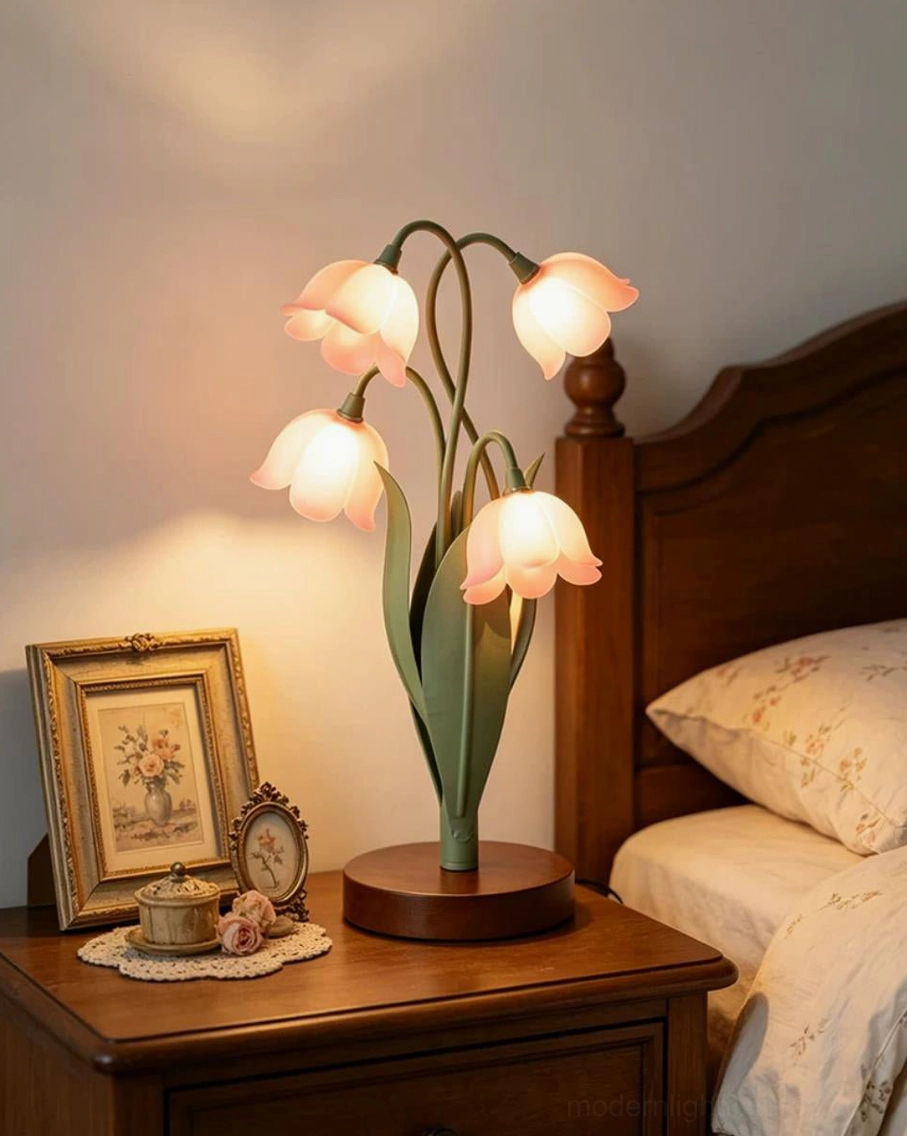 Campelle bell-flower lamp lit with warm light on bedroom nightstand with vintage clock and framed decor, cozy bedroom ambiance