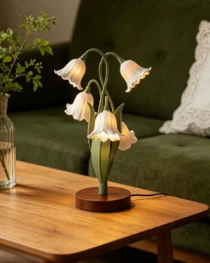 Campelle table lamp with bell-flower blooms placed on living room coffee table next to green sofa and plant vase, lifestyle setting