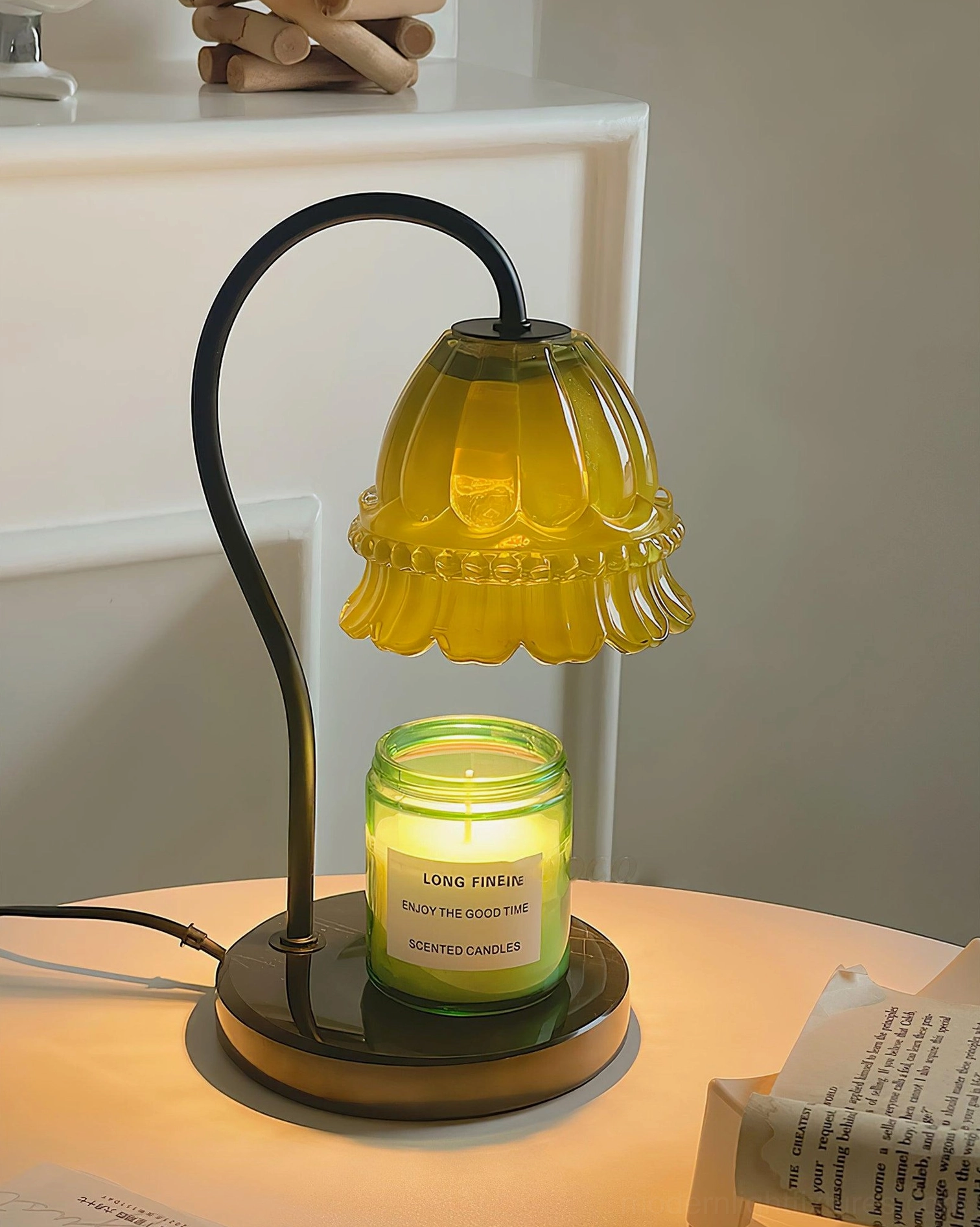 Yellow floral glass candle warmer lamp with black metal stand on bedside table