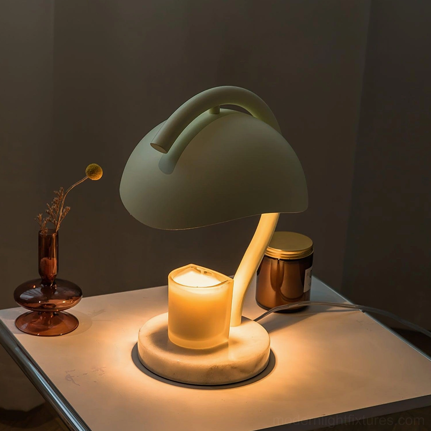 Sage green candle warmer table lamp on dark brown side table with lit scented candle and natural alabaster base