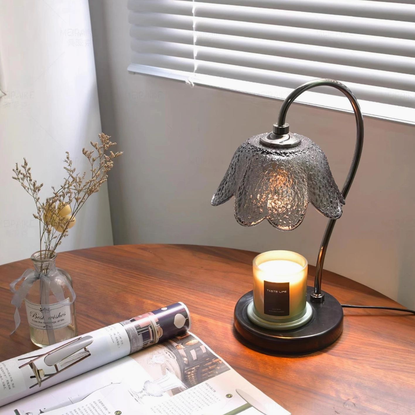 Modern table candle warmer lamp displayed on wooden round table with dried flowers and magazines
