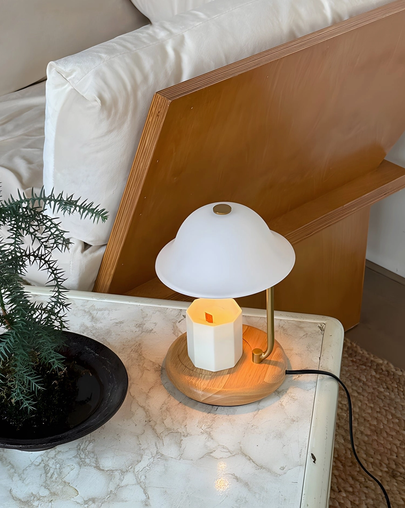 Contemporary table lamp with integrated candle warmer on marble side table with natural wood base