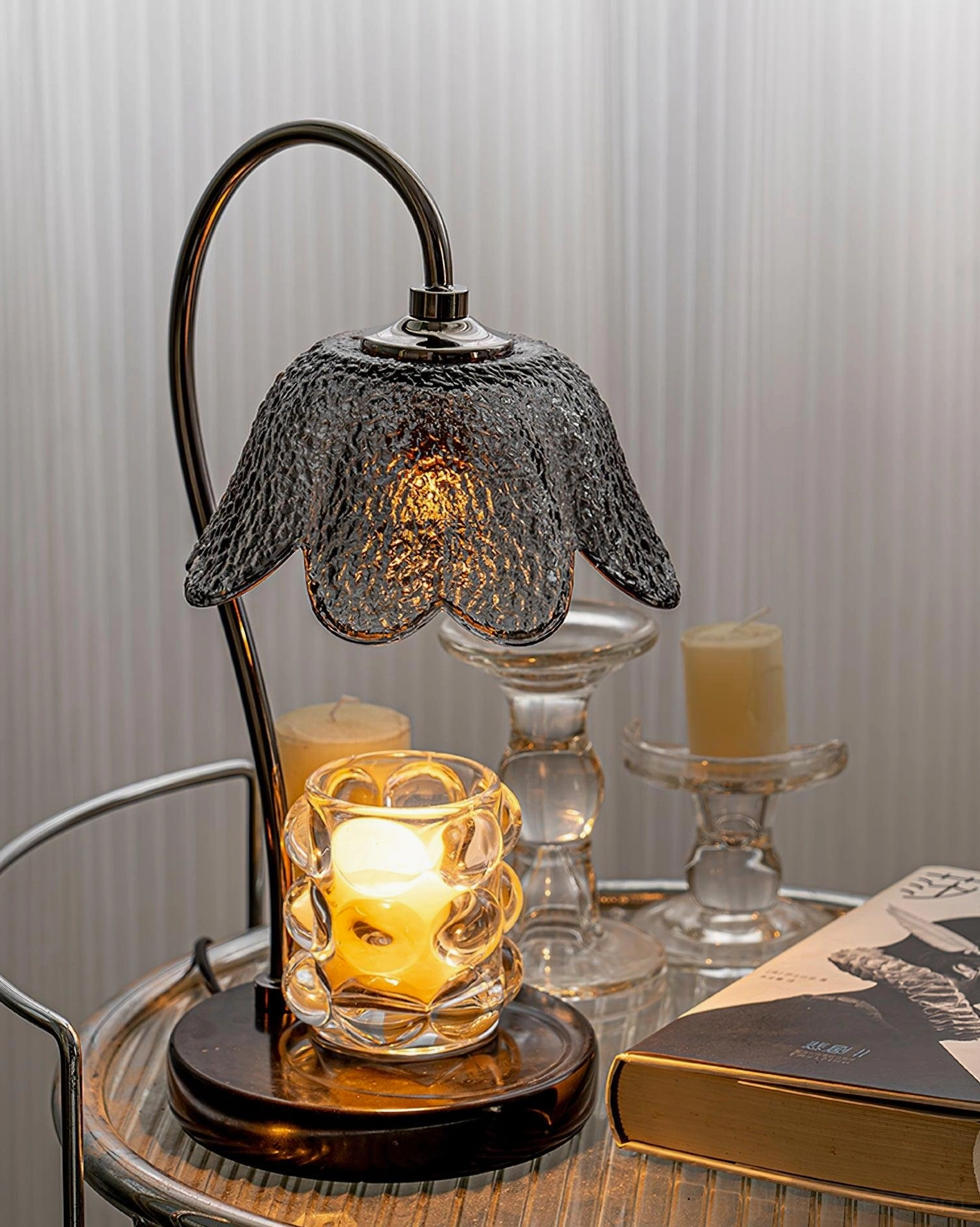 Decorative candle warmer lamp on metal side table with multiple candles and books warm ambient lighting