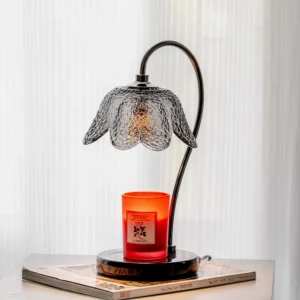 Modern table candle warmer lamp with scented candle displayed on book with sheer curtain background
