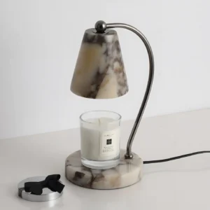 Contemporary table candle warmer lamp with marble shade and base, three-quarter perspective with lit scented candle